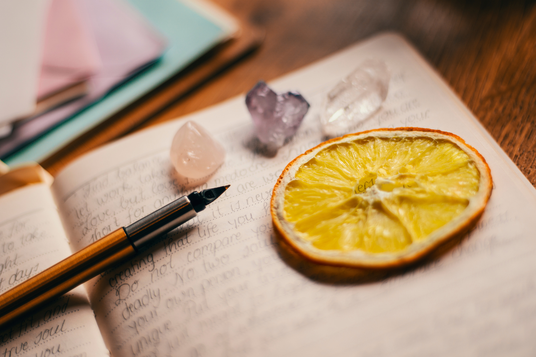 Orange Slice on top of Open Book next to a Pen